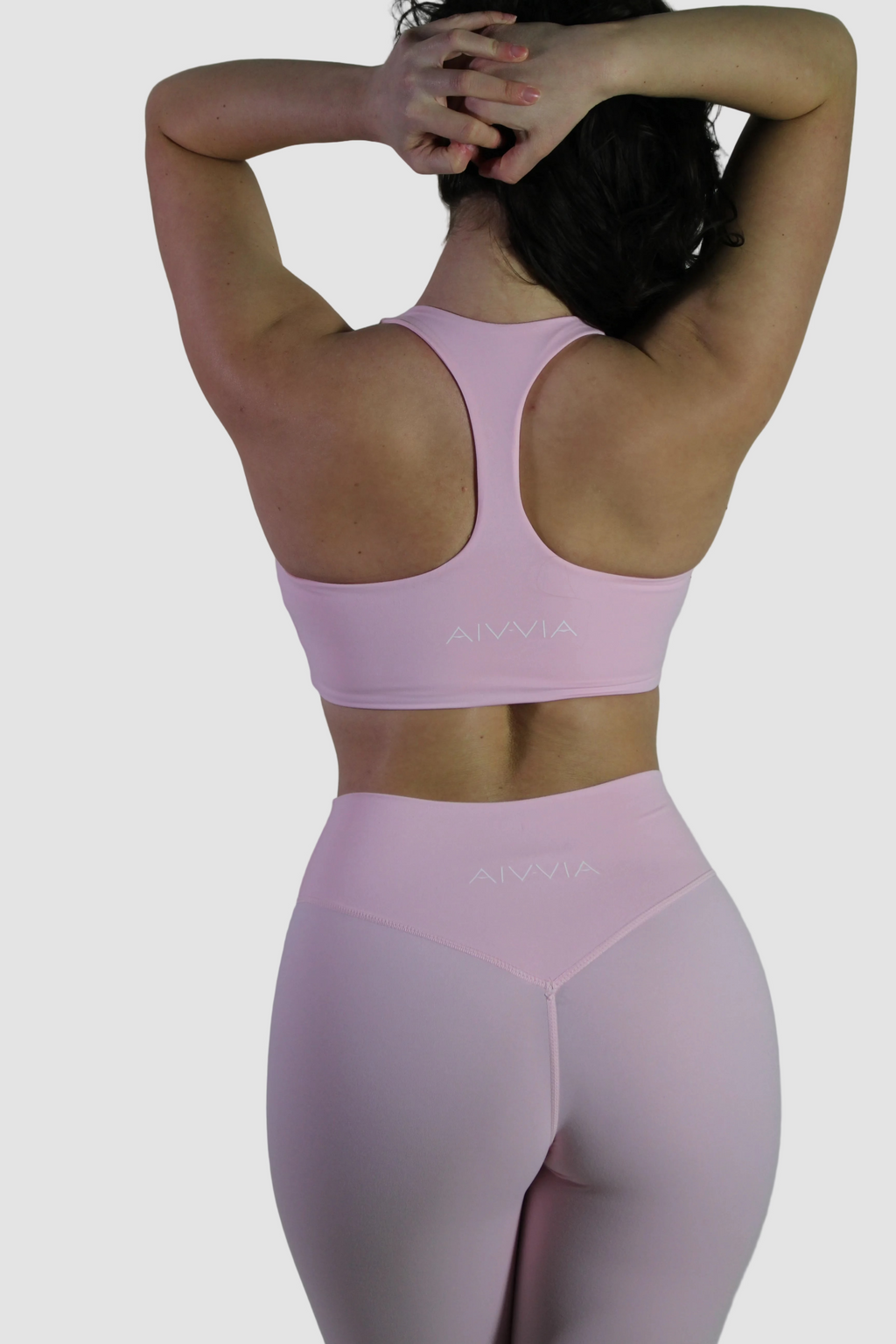 Back view of Aivvia Athletics pink sports bra back, highlighting logo on ribbed underband below Y-back panel.