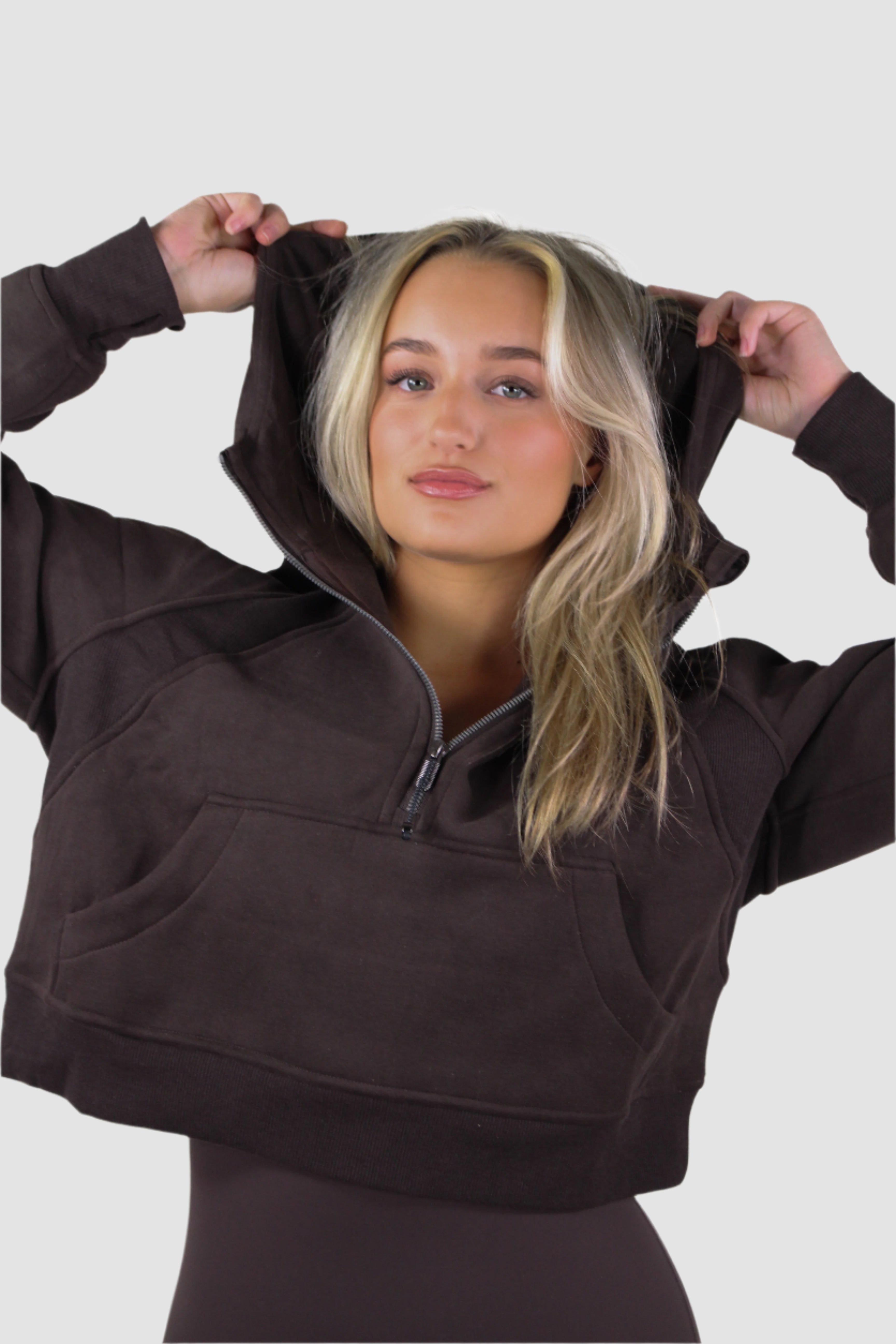 Athletic women's cropped quarter zip hoodie by Aivvia Athletics, deep brown, hood on, stylish workout gear.