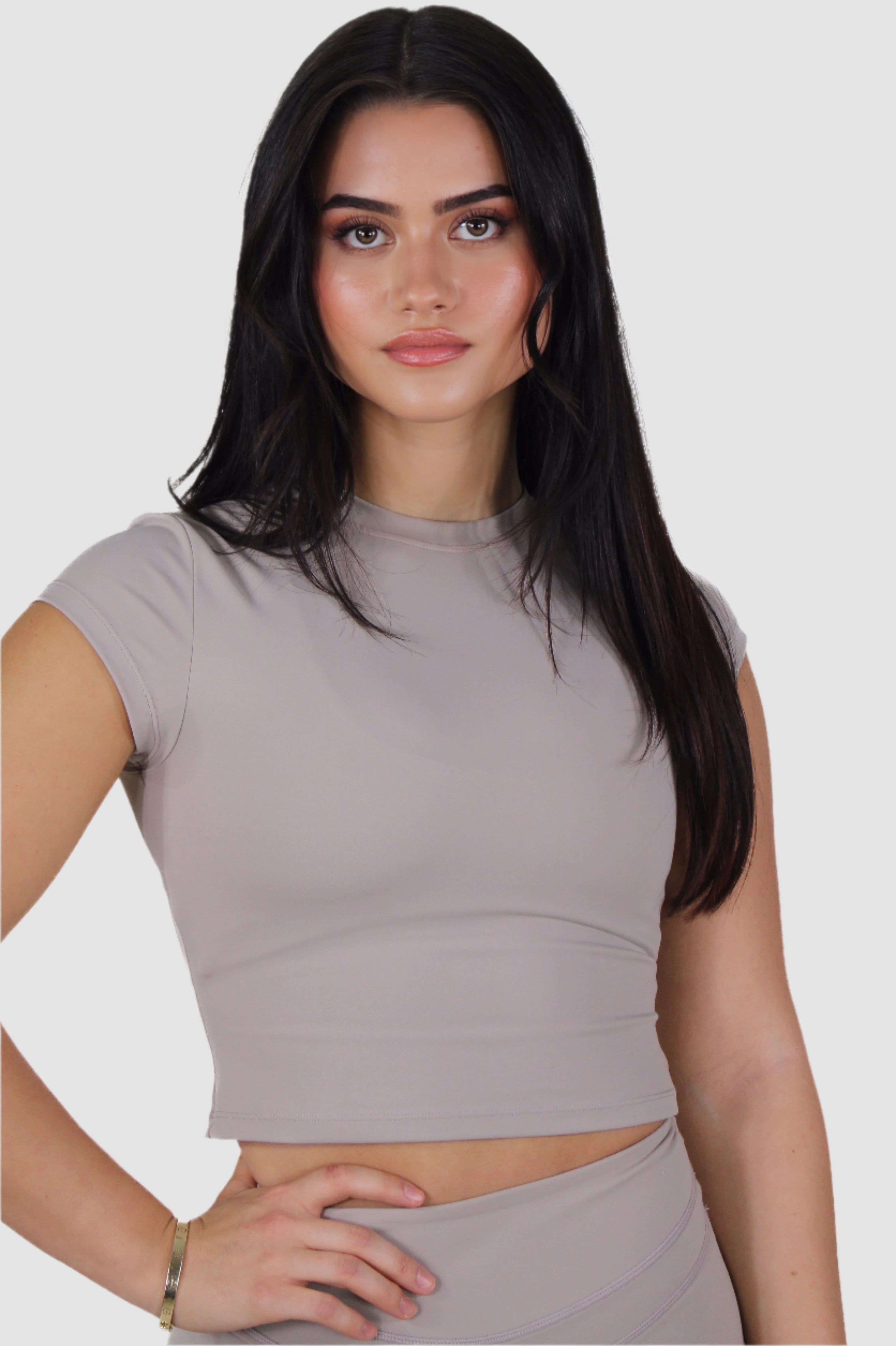 Woman in taupe Aivvia Athletics crop top and leggings; sleek, minimal activewear perfect for fitness and casual style.