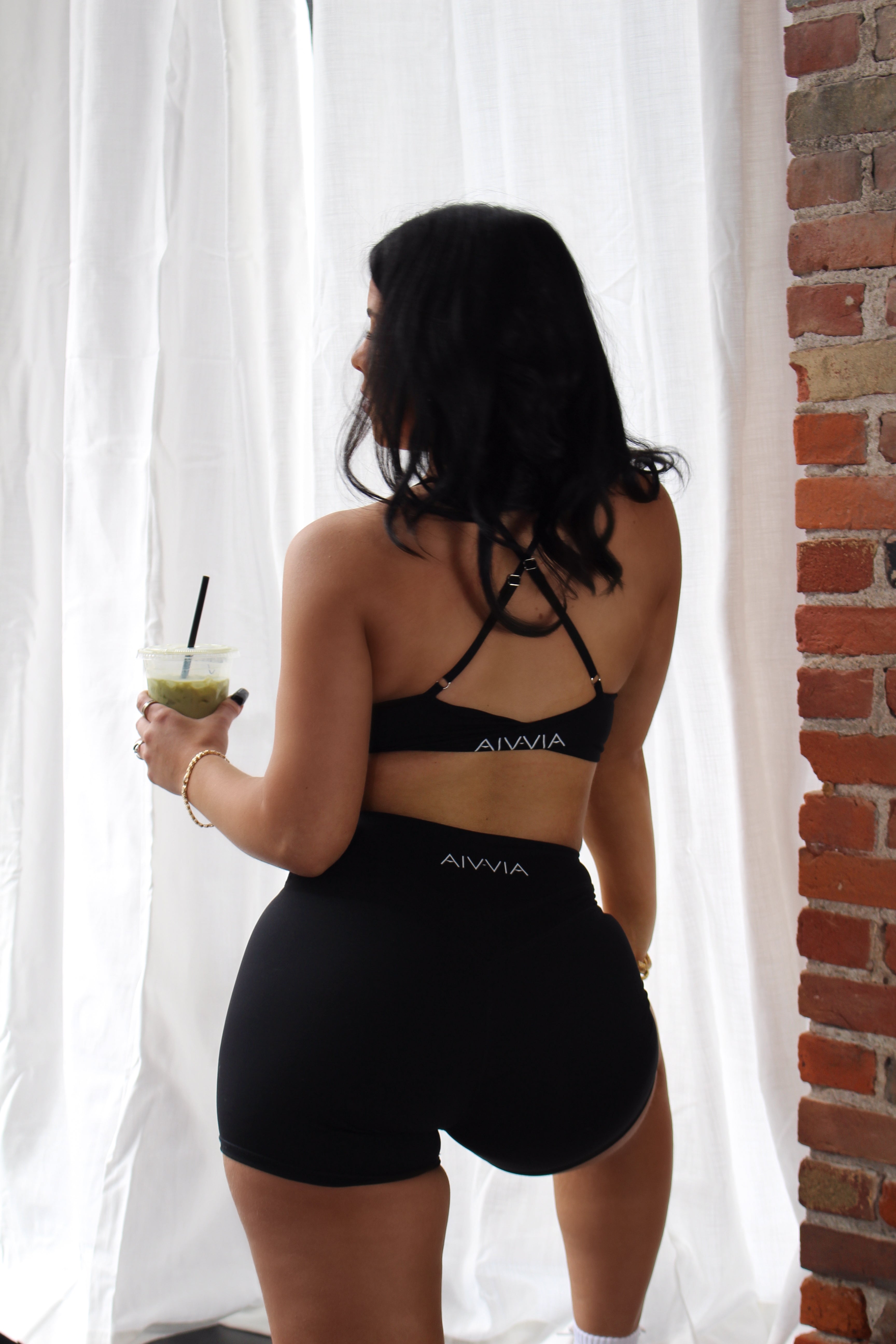 Black Aivvia Athletics sports bra with crisscross back straps; lightweight and breathable for training.