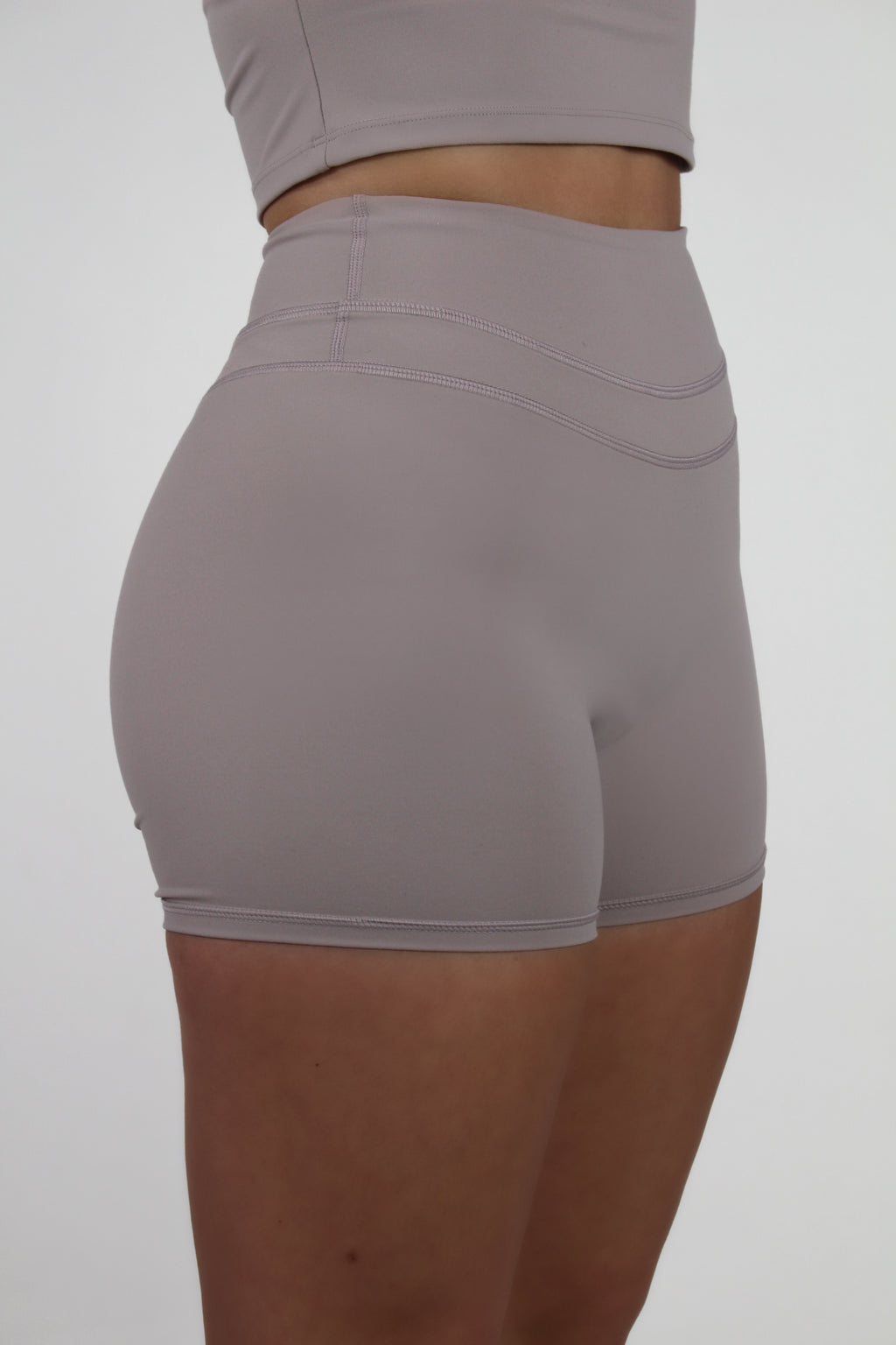 Woman in taupe Aivvia Athletics shorts; high-waisted, body-contouring fit for fitness and leisure.