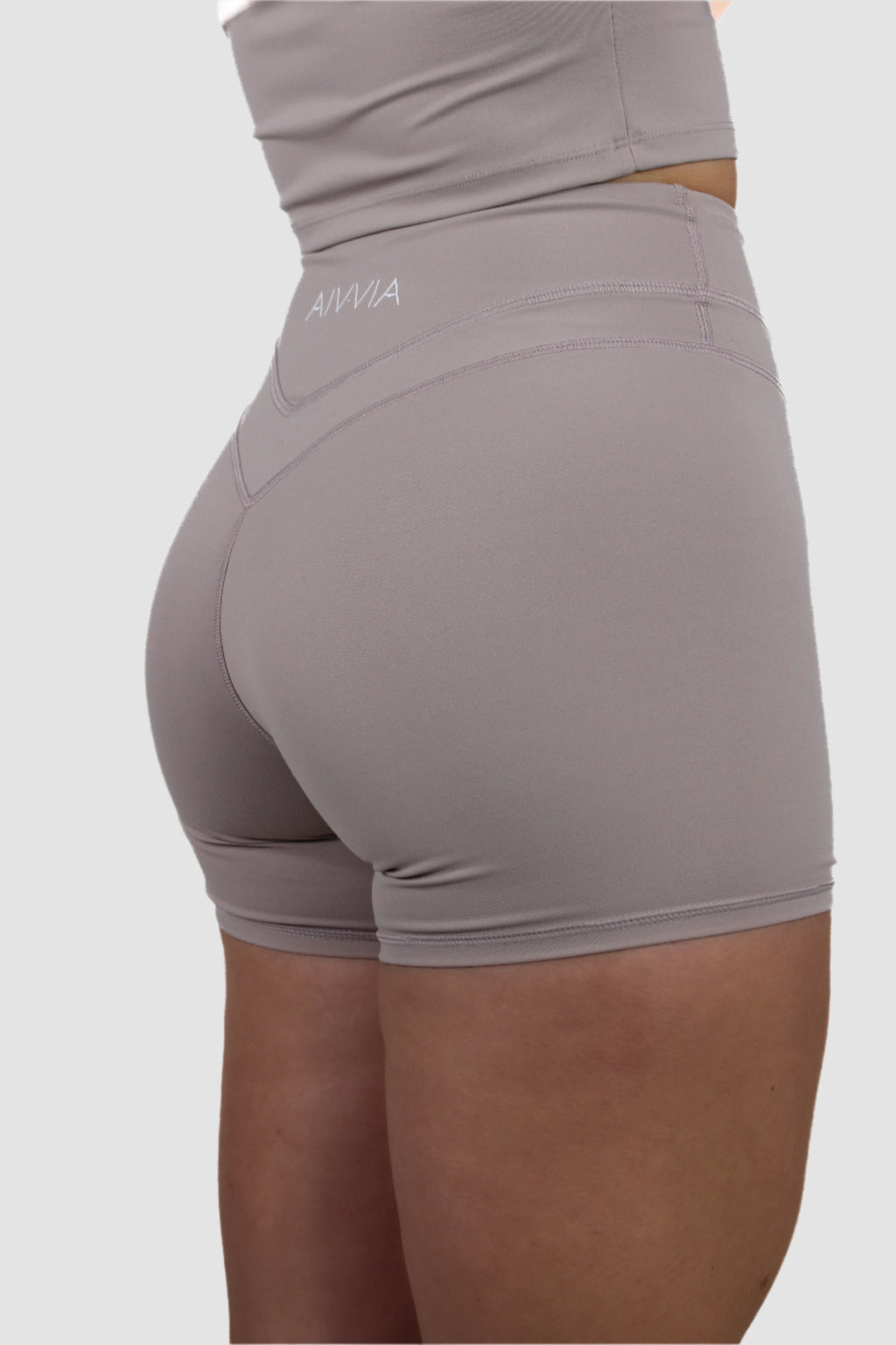 Angled back view of light taupe Aivvia Athletics high-waisted shorts with sculpted seam details.