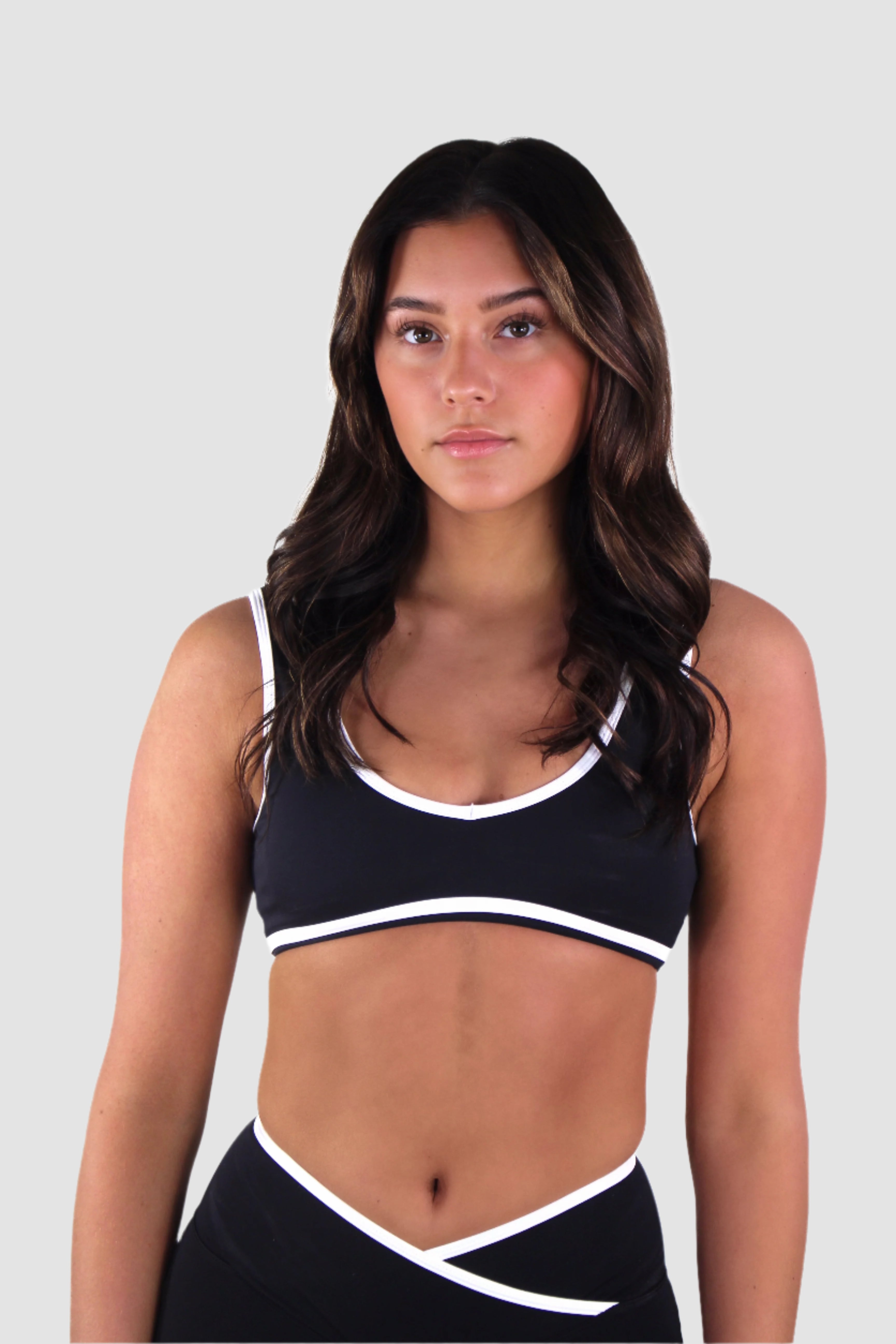 Front view of black Aivvia Athletics sports bra with white trim, sculpting athleticwear for women.