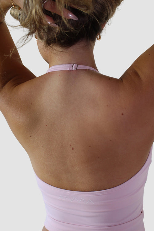 Back view of a person wearing a pink dress against a plain background