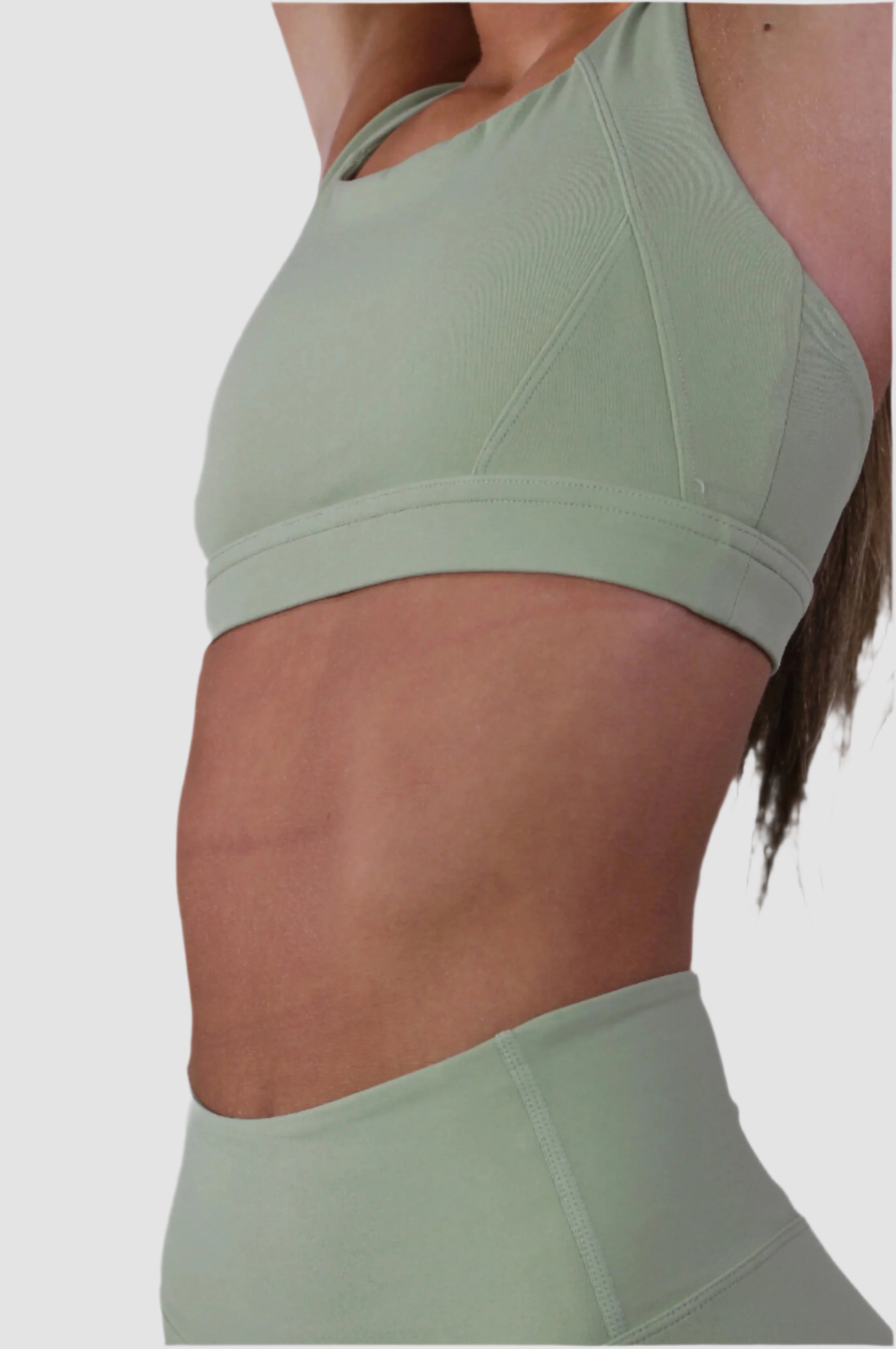 Side view of Aivvia Athletics sage green sports bra showing mesh panel accents and ergonomic strap placement.