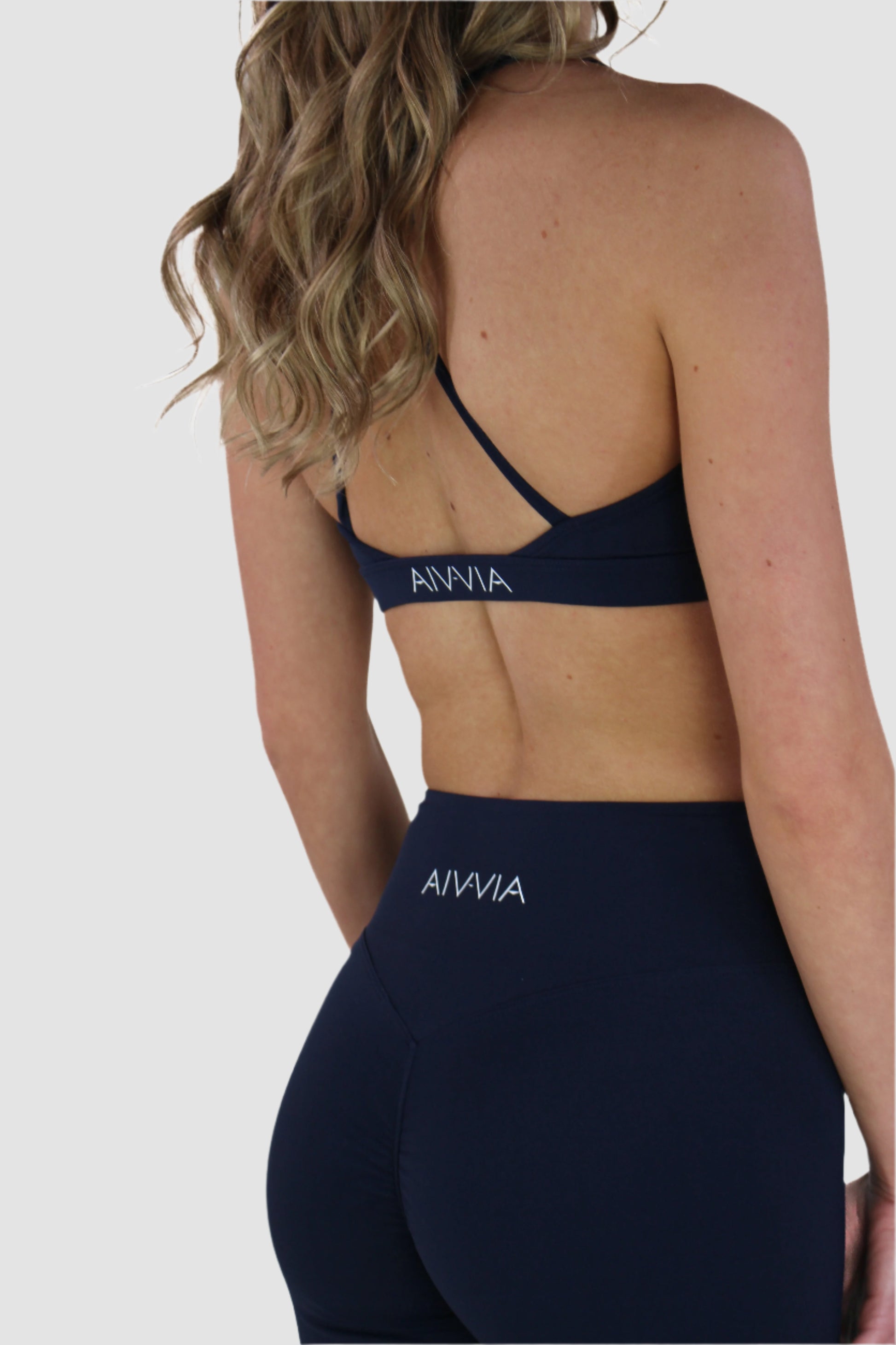 Full back view of navy Aivvia Athletics sports bra showing strappy design and mid-back cut.