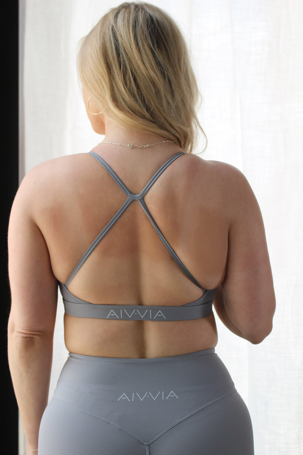 Back view of Aivvia Athletics criss-cross sports bra and gray leggings – breathable and functional activewear for women’s workouts.