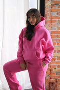 Woman wearing pink Aivvia Athletics hoodie and matching sweatpants, cozy fit for training or lounging.
