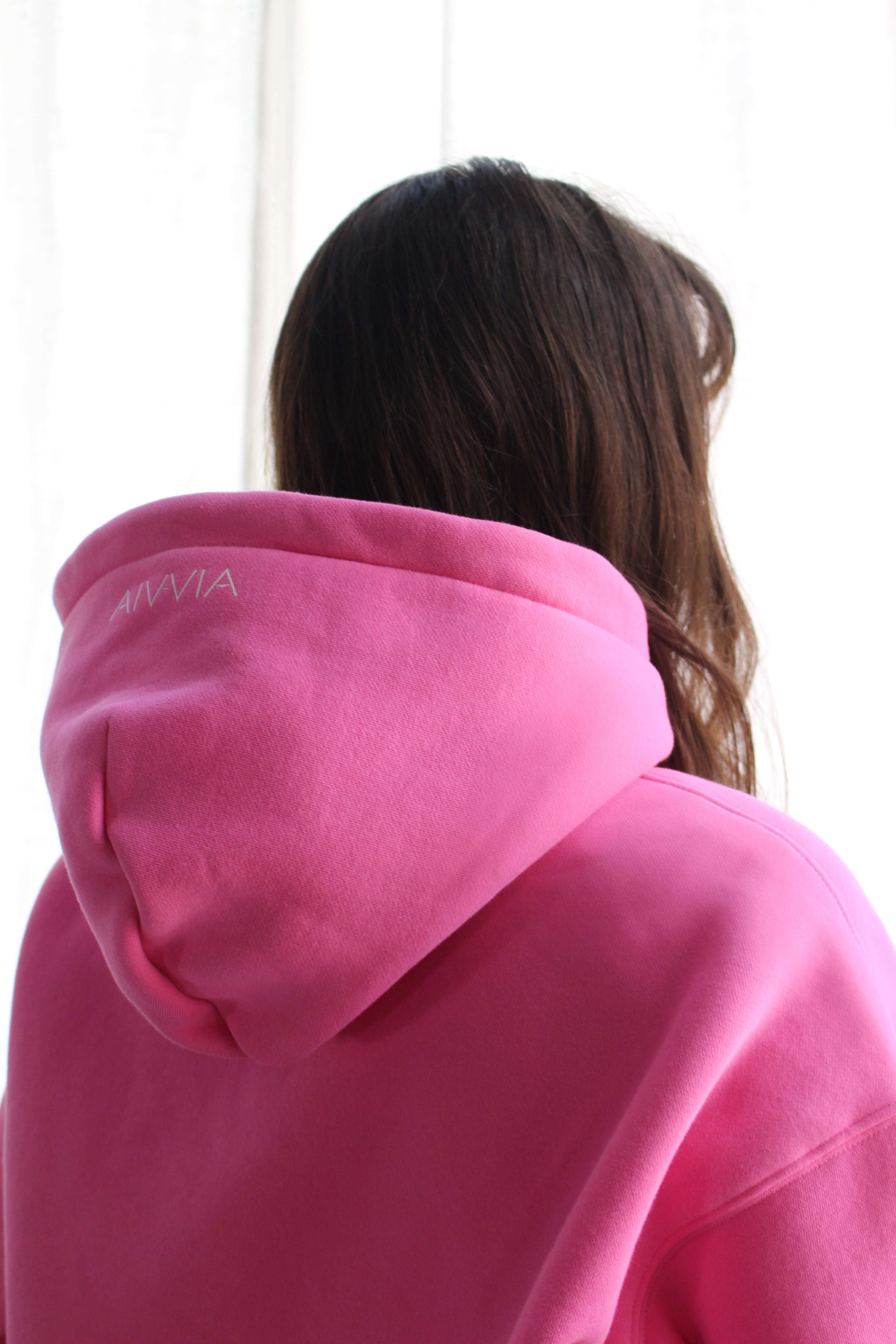 Hood detail of woman wearing pink Aivvia Athletics hoodie, showing drawstring and stitching.