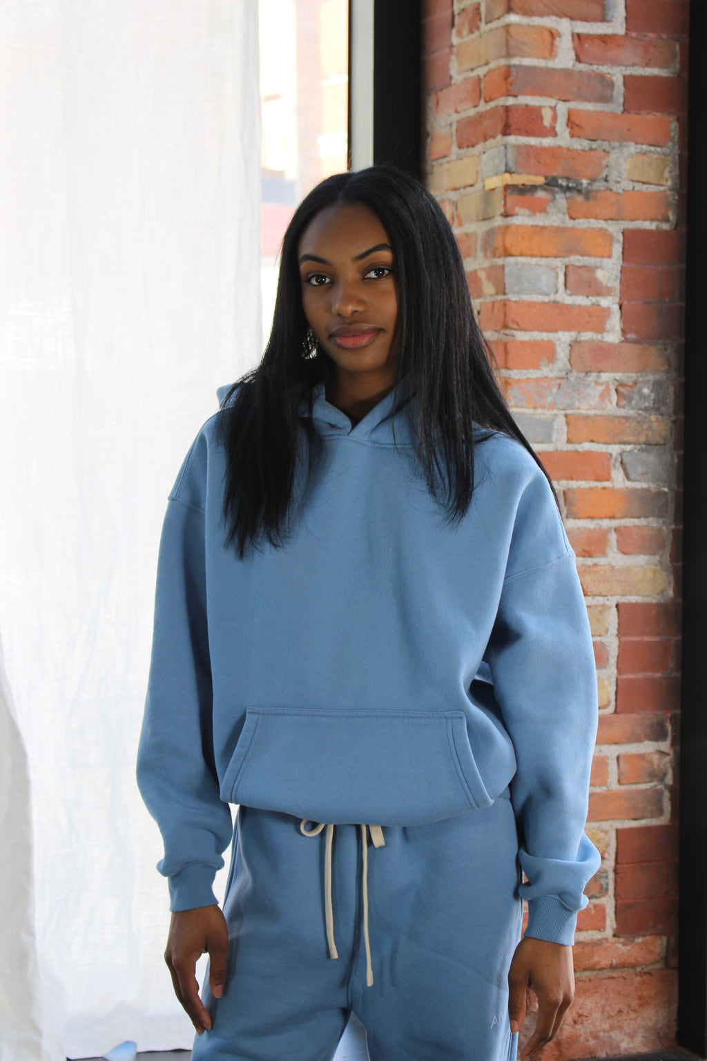 Front view of light blue Aivvia Athletics hoodie; casual, minimalist style with dropped shoulders and relaxed fit.