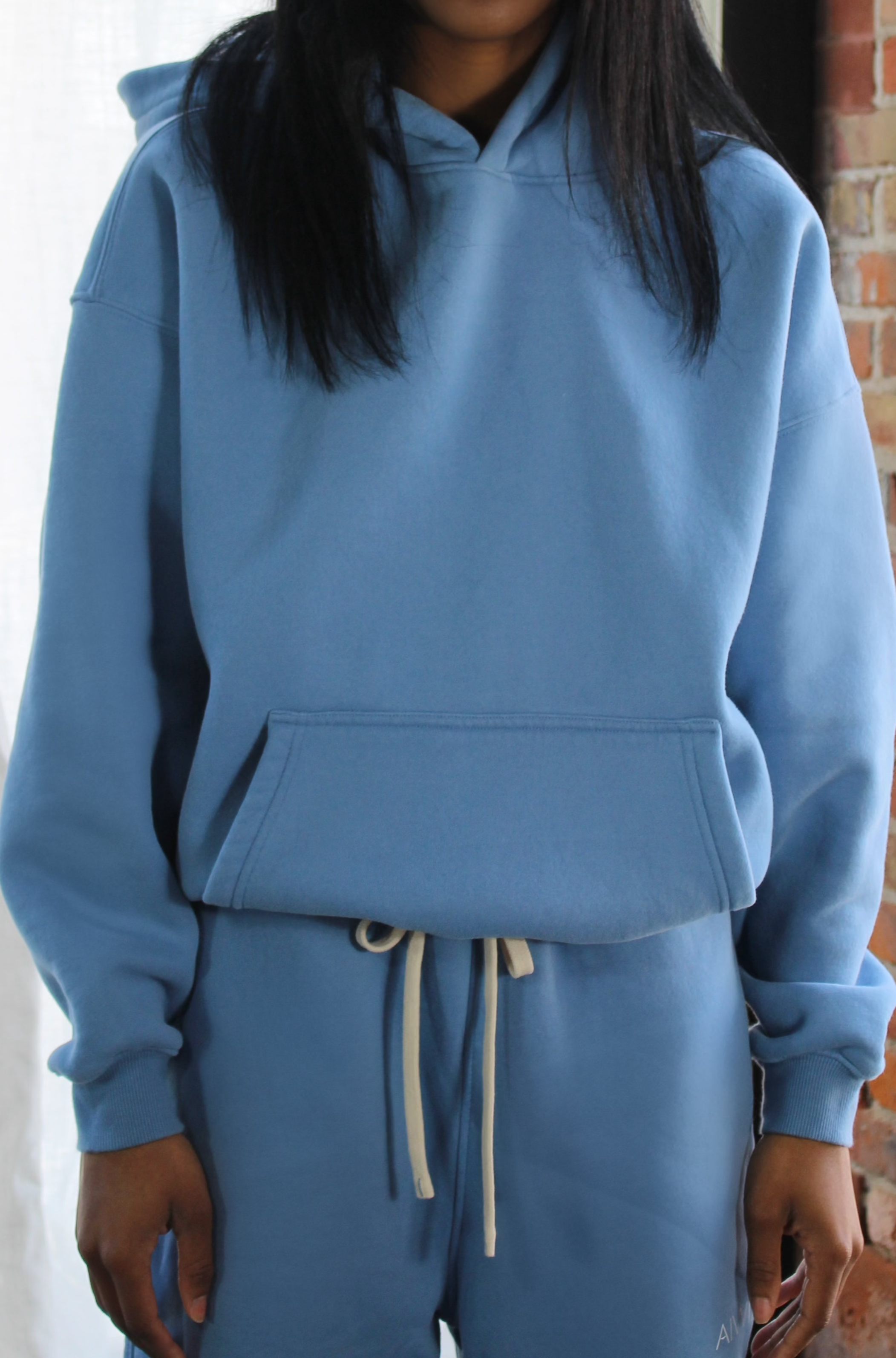 Cropped view of Aivvia Athletics light blue hoodie showing ribbed cuffs, drawstring, and soft fleece fabric detail.