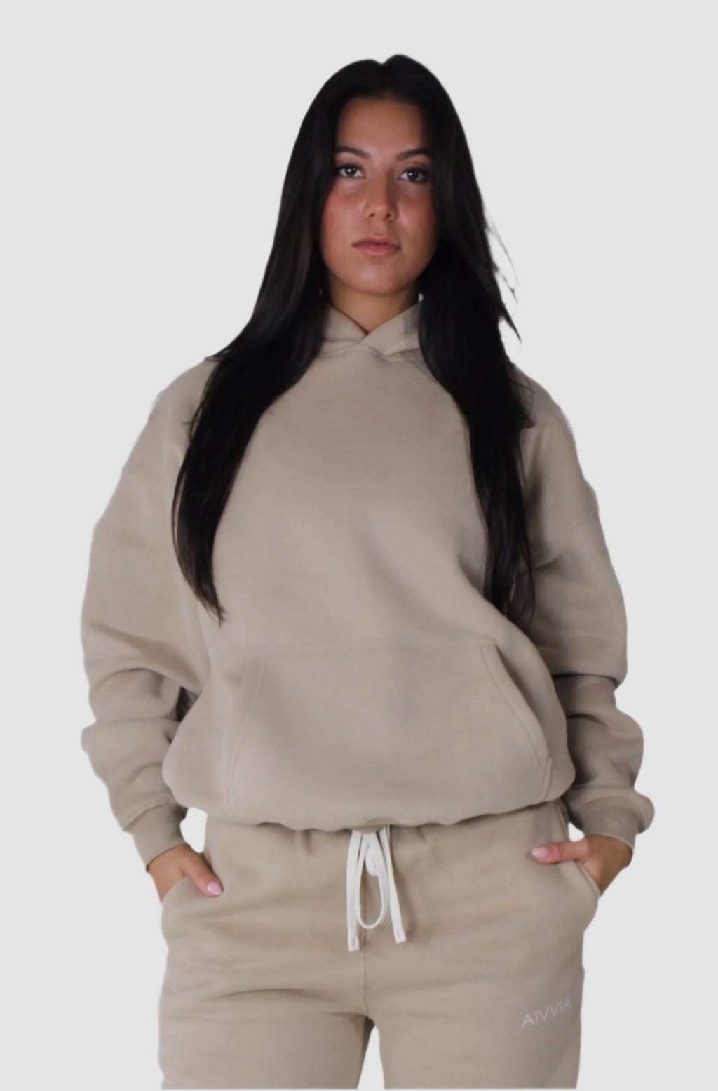 Neutral beige Aivvia Athletics hoodie styled with matching joggers; everyday athleisure with a soft, clean finish.