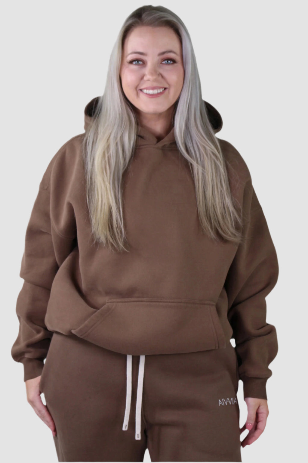 Warm brown Aivvia Athletics hoodie with front pocket and relaxed hood; soft fleece blend for all-day comfort.
