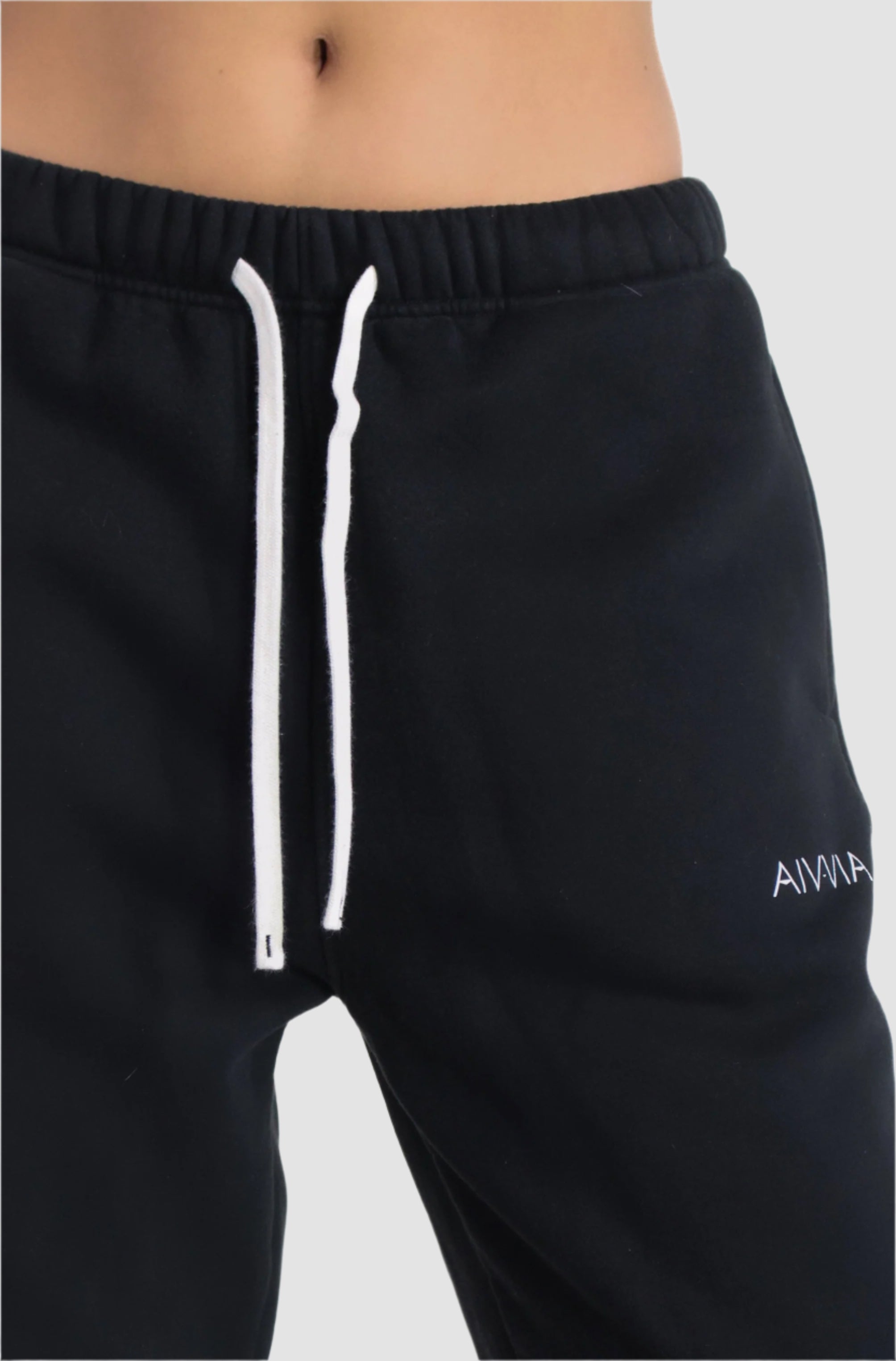 Close-up of black Aivvia Athletics sweatpants, logo detail and drawstring waist for secure fit.
