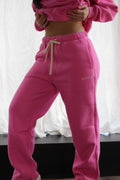 Bright pink Aivvia Athletics sweatpants styled with cropped hoodie; bold, confident, and ultra-soft for lounge or gym.