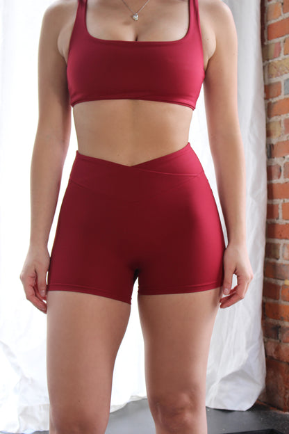 Closeup of high-rise red shorts from Aivvia Athletics with clean seam lines and stretch-fit waistband.