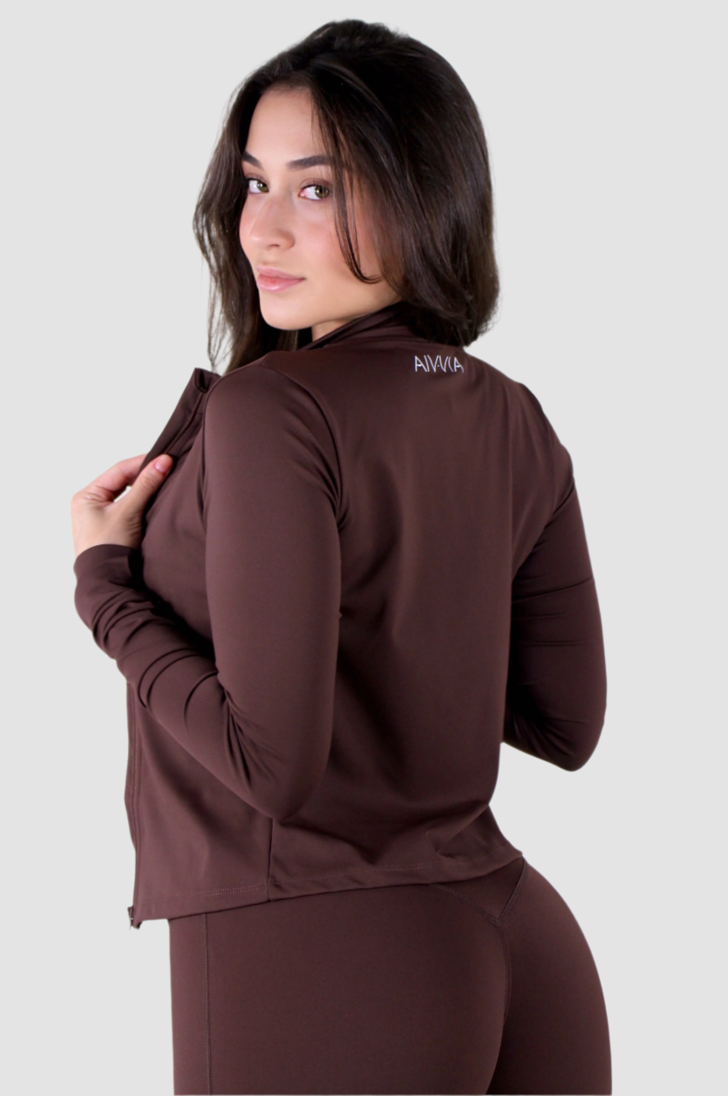 Back view of brown Aivvia Athletics long-sleeve fitted jacket showing smooth, seamless design.