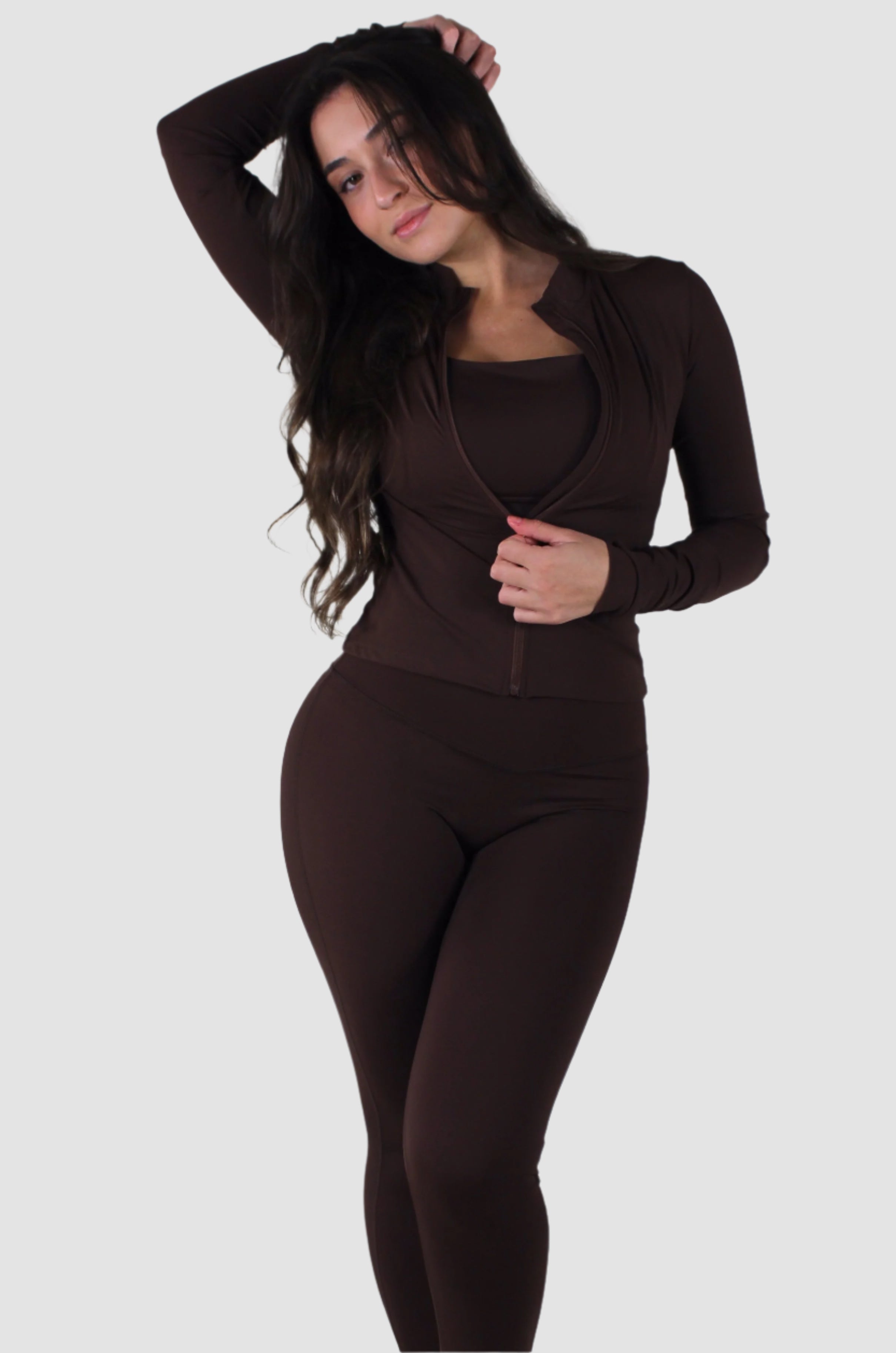 Woman wearing brown Aivvia Athletics zip-up jacket with high collar, paired with matching leggings.