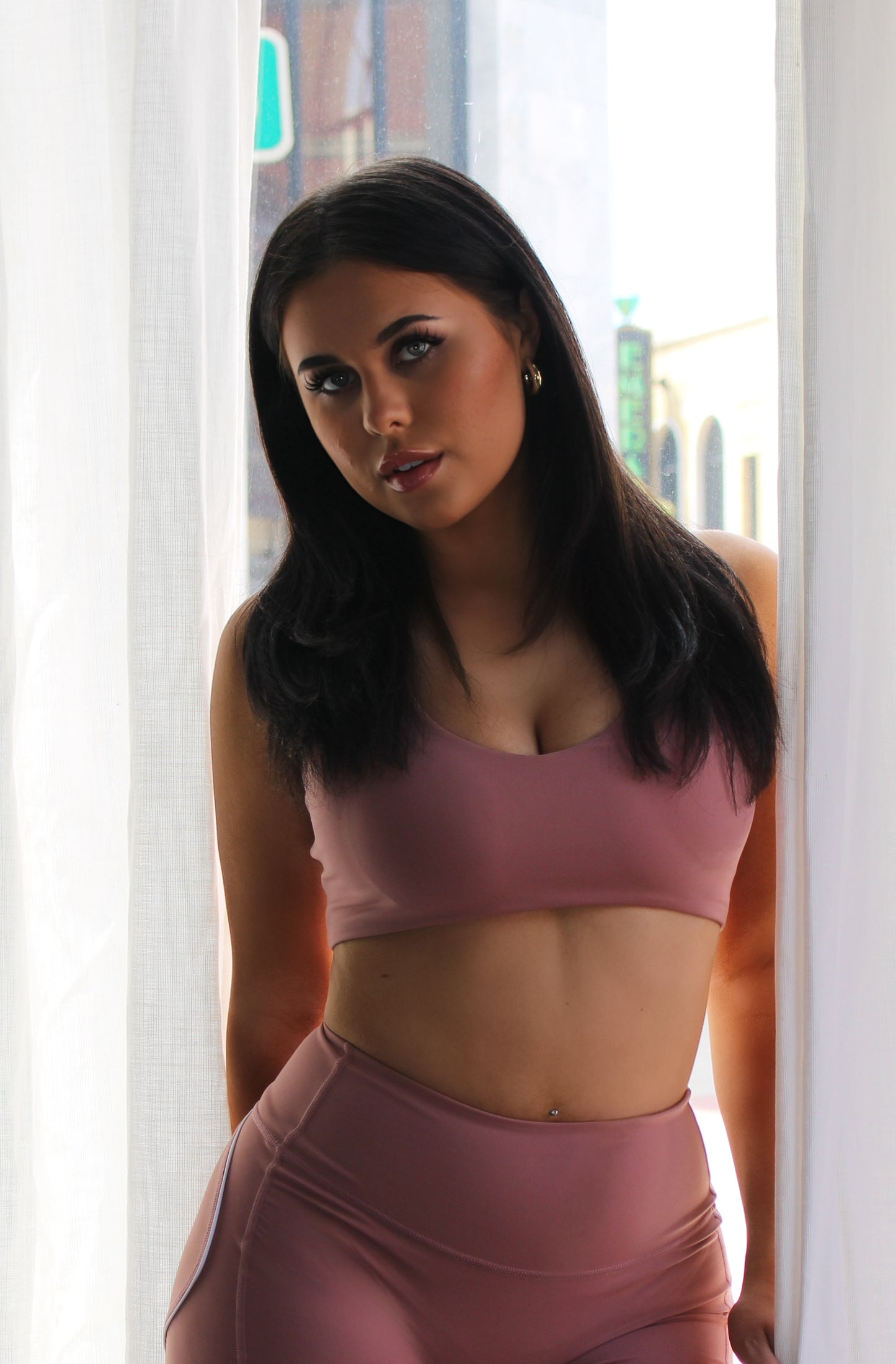 Blush pink seamless Aivvia Athletics sports bra with scoop neckline and wide straps for flexible, light-support performance.