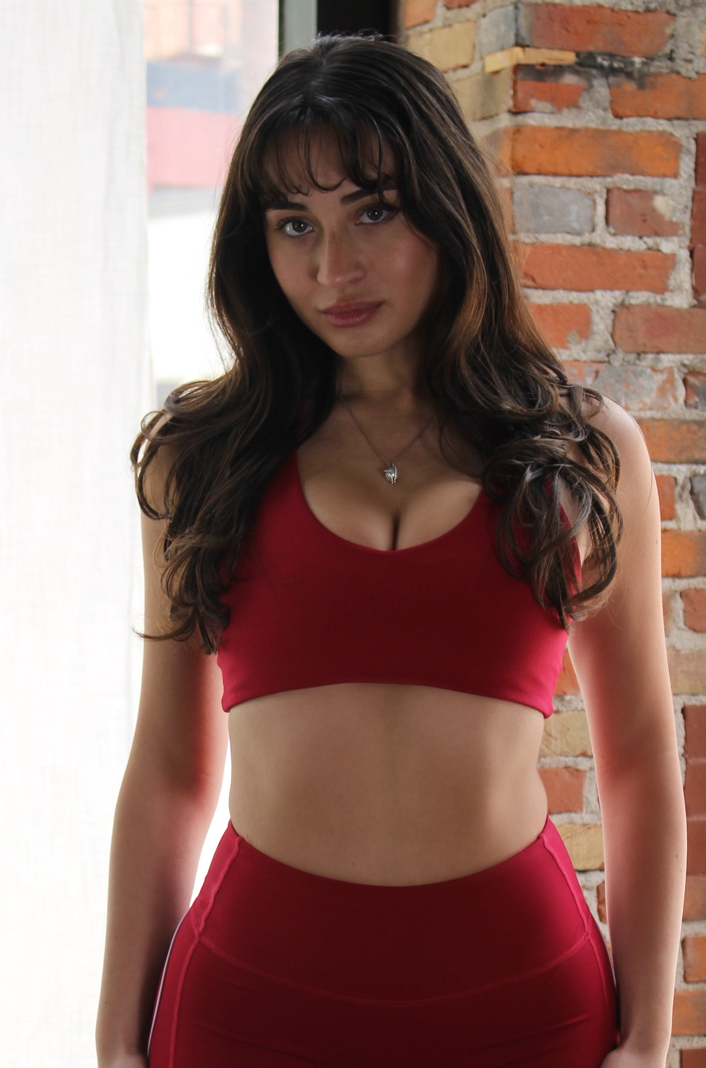 Deep red scoop-neck Aivvia Athletics sports bra with seamless support design and mid-impact coverage.