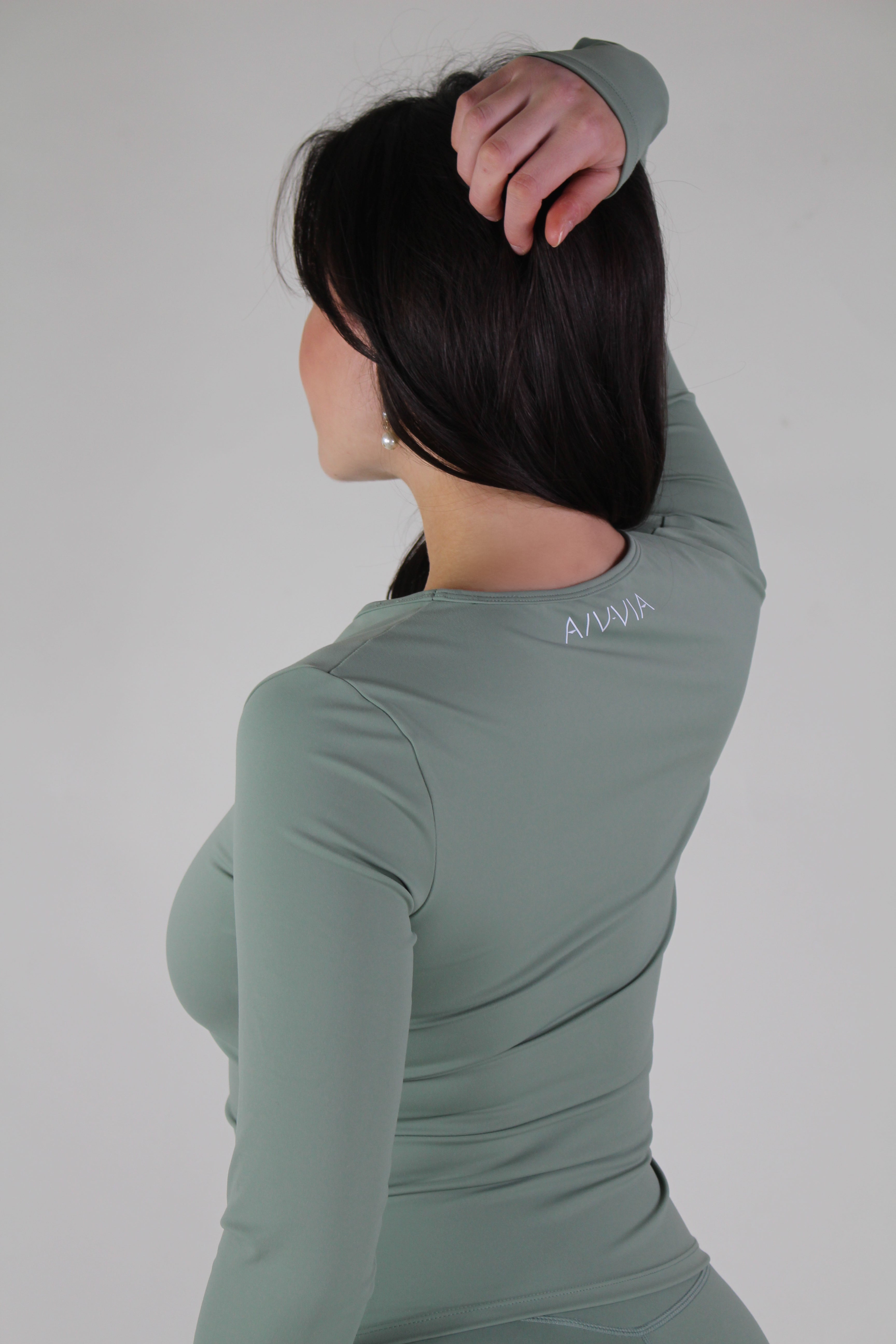 Back view of Aivvia Athletics Tone Long Sleeve in sage green, showing fitted seamless design and full-length coverage for women’s workouts.